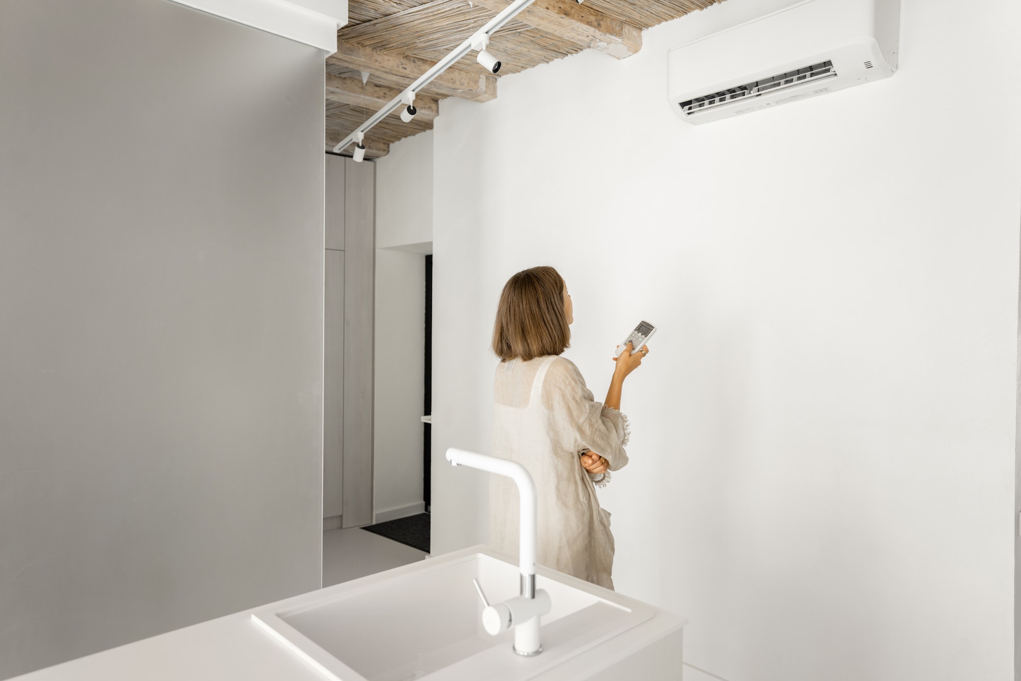 Woman sets the temperature on the air conditioner at home